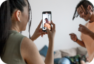 A lady recording a video of a man using a smart phone.
